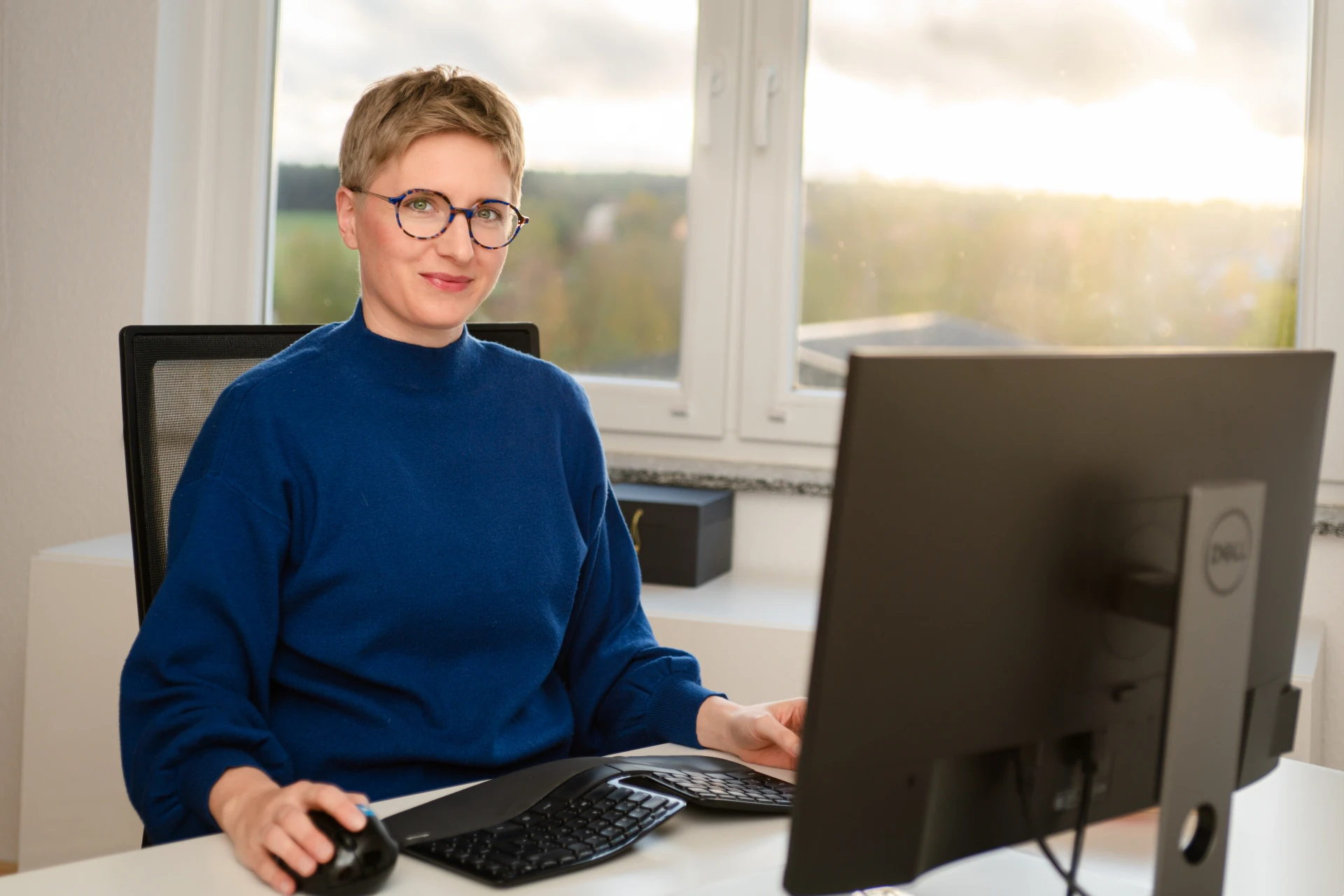 Kathrin Pfaff am Schreibtisch, blickt lächelnd in die Kamera